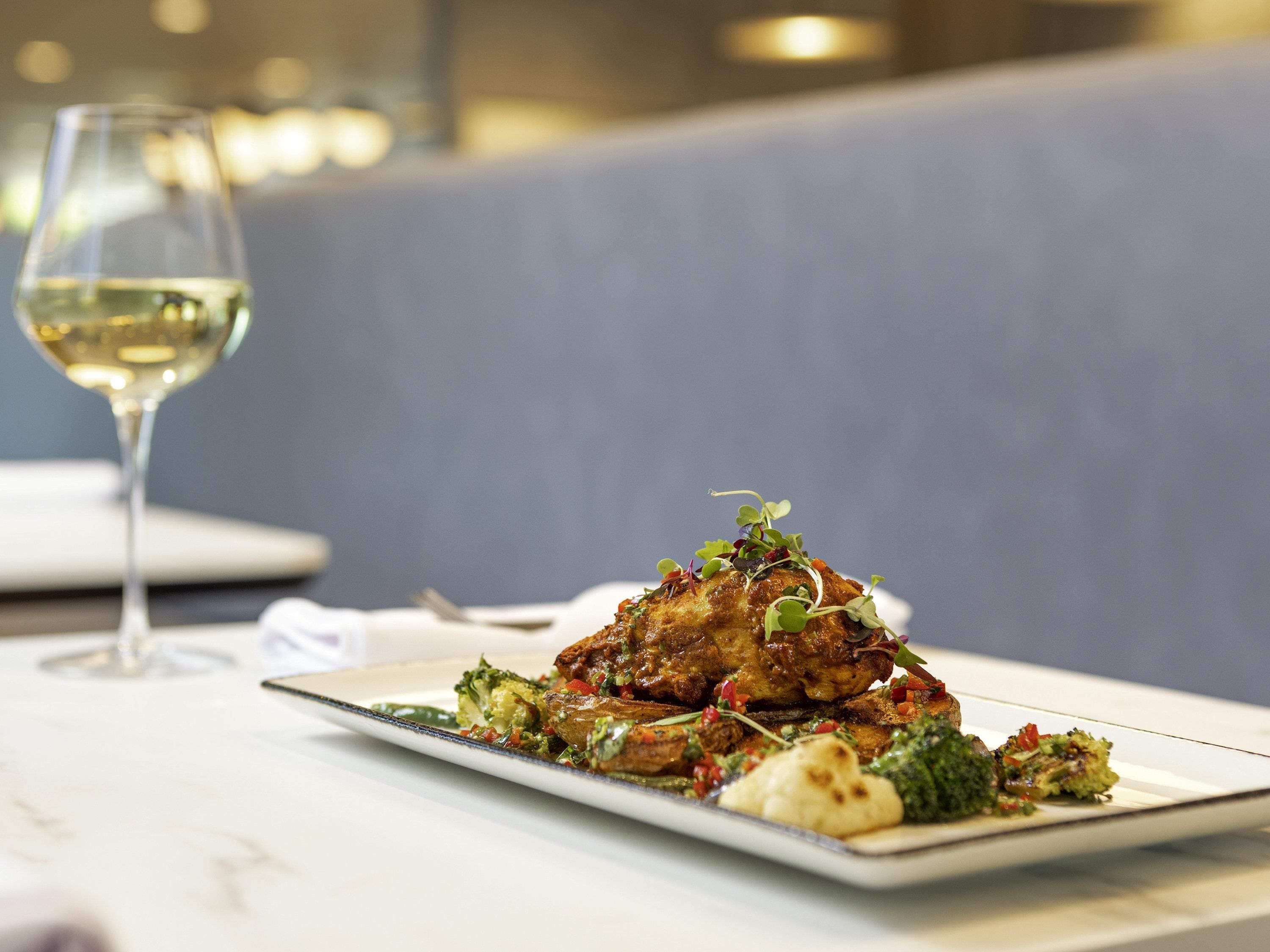 Un plato de comida con una copa de vino blanco sobre una mesa.