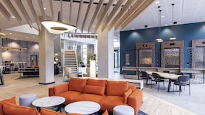 A modern hotel lobby with a central seating area, a staircase, and a reception desk. - Novotel Liverpool Paddington Village (Liverpool)
