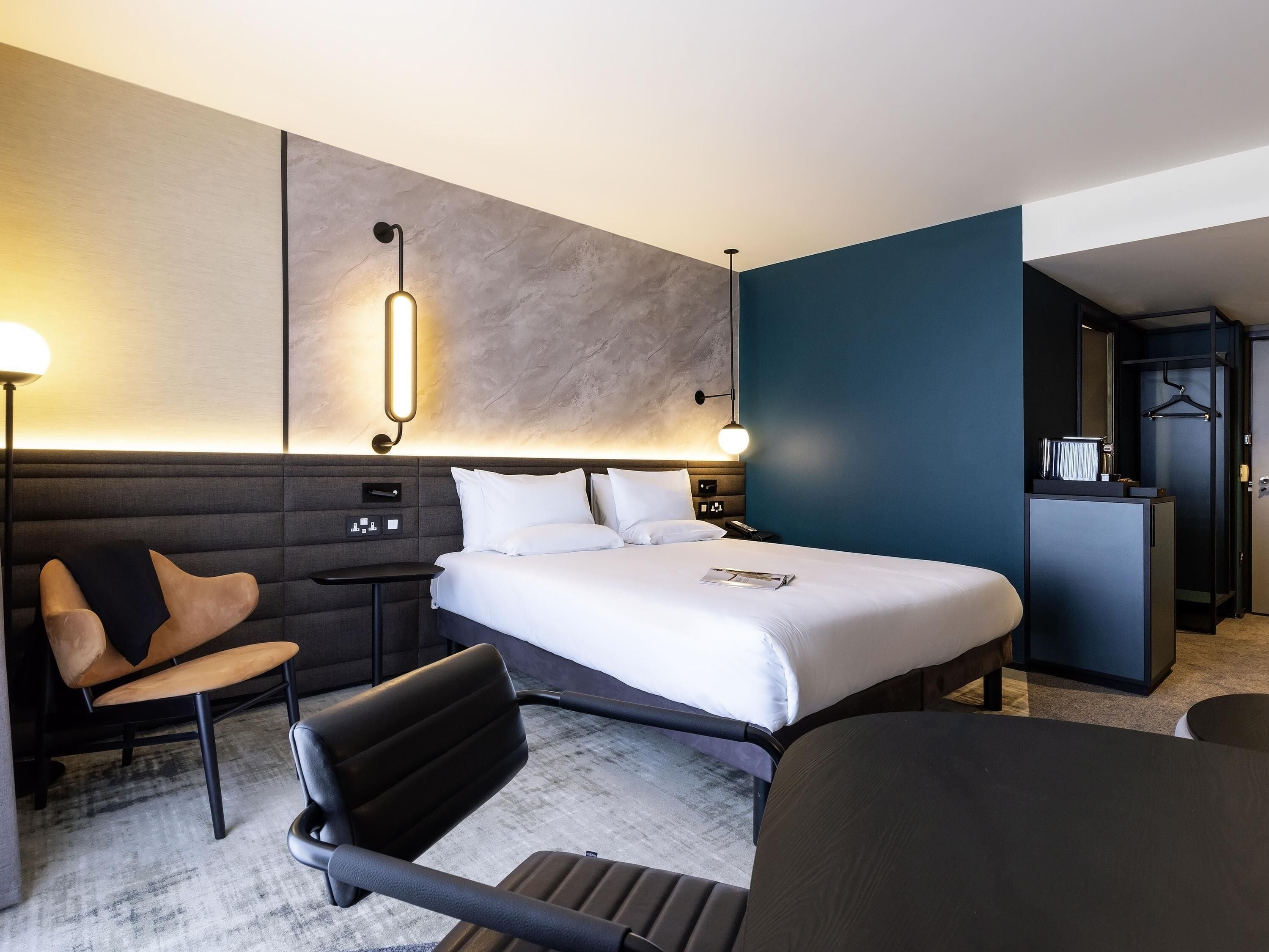 Een moderne hotelkamer met een groot bed, een bureau, een stoel en een nachtkastje.