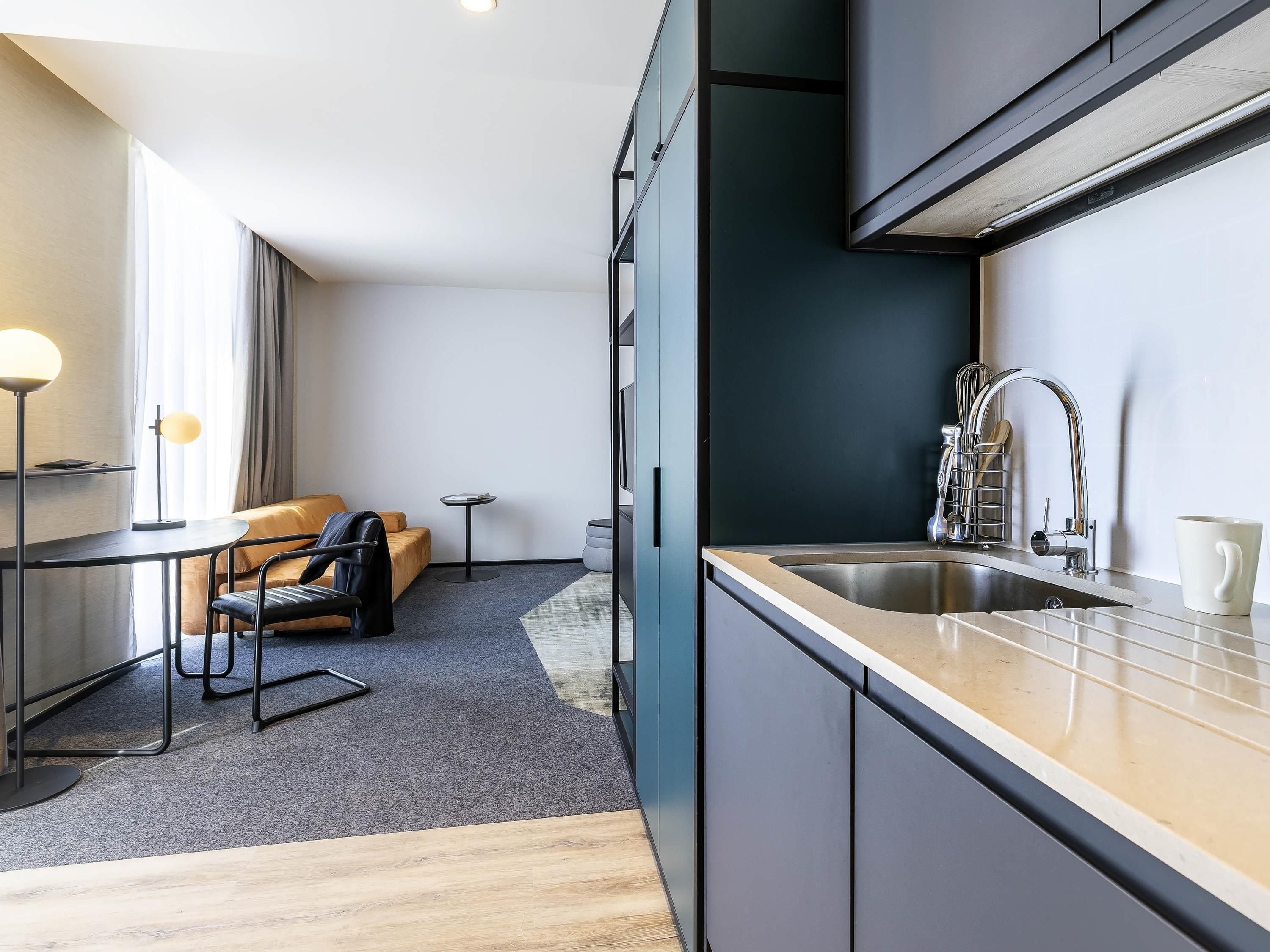 A modern kitchen with a sink, a coffee maker, and a small dining area with a table and chairs.