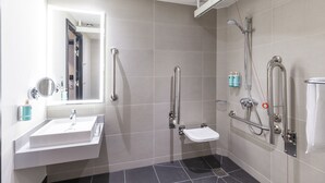 A modern bathroom with a white sink, a handheld showerhead, and a handheld toilet. - Novotel Liverpool Paddington Village (Liverpool)