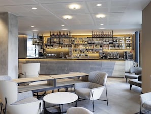 Eine Bar mit Sitzgelegenheiten, eine Theke mit Weinauslage und eine Treppe.