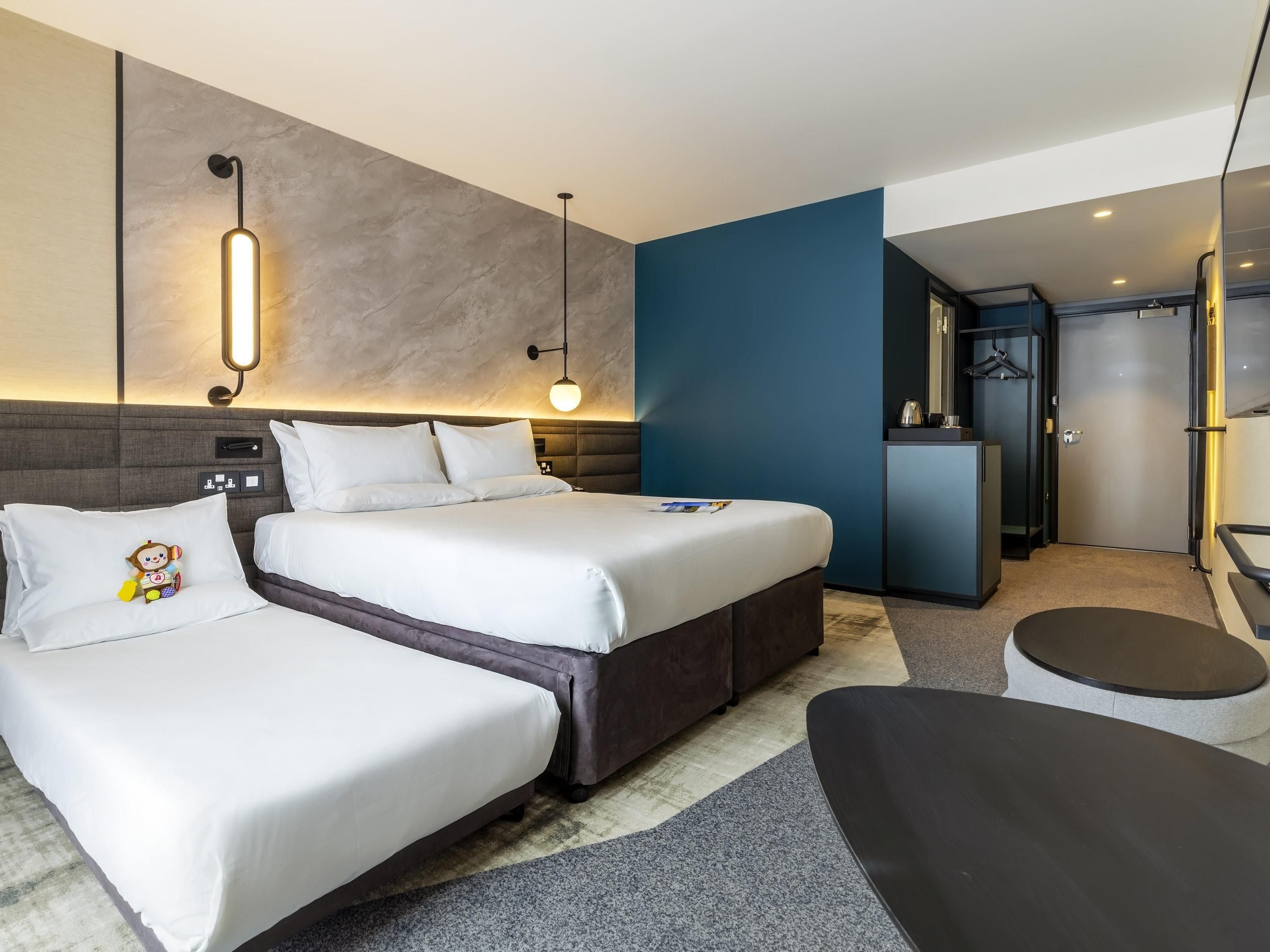 A modern hotel room with a large bed, bedside tables, a desk, and a seating area.