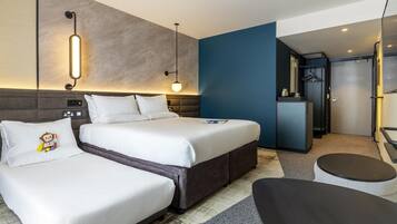 A modern hotel room with a large bed, bedside tables, a desk, and a seating area.