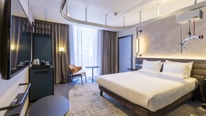 A modern hotel room with a large bed, a desk, a chair, a small table, and a large mirror. - Novotel Liverpool Paddington Village (Liverpool)