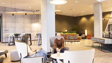 A modern lounge area with seating, a coffee table, and a large plant.