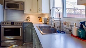 A kitchen with stainless steel appliances, a double sink, and a window with a view of a fence.