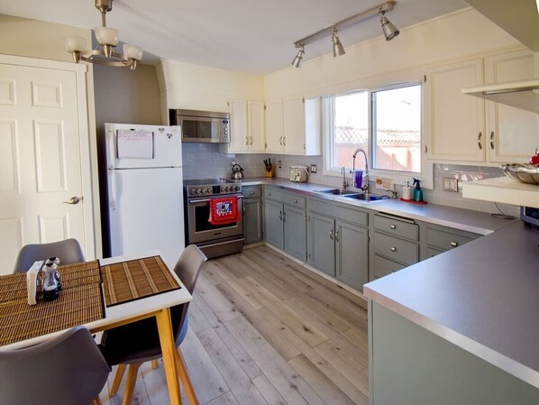 A compact kitchen with a refrigerator, microwave, stove, and sink.