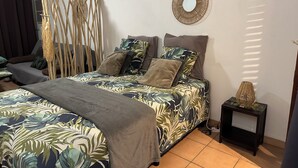 A bedroom with a bed, a bedside table, a mirror, and a curtain. - Studio "Entre Terre et Mer" Residence Anse des Sables (Marigot)