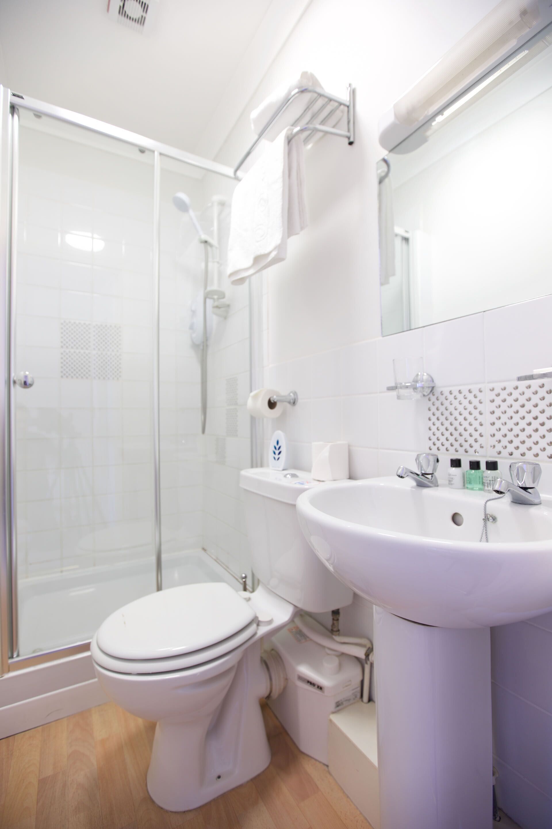 Un baño moderno con ducha de vidrio, lavamanos blanco y retrete.