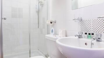 A modern bathroom with a glass-enclosed shower, a white sink, and a toilet.