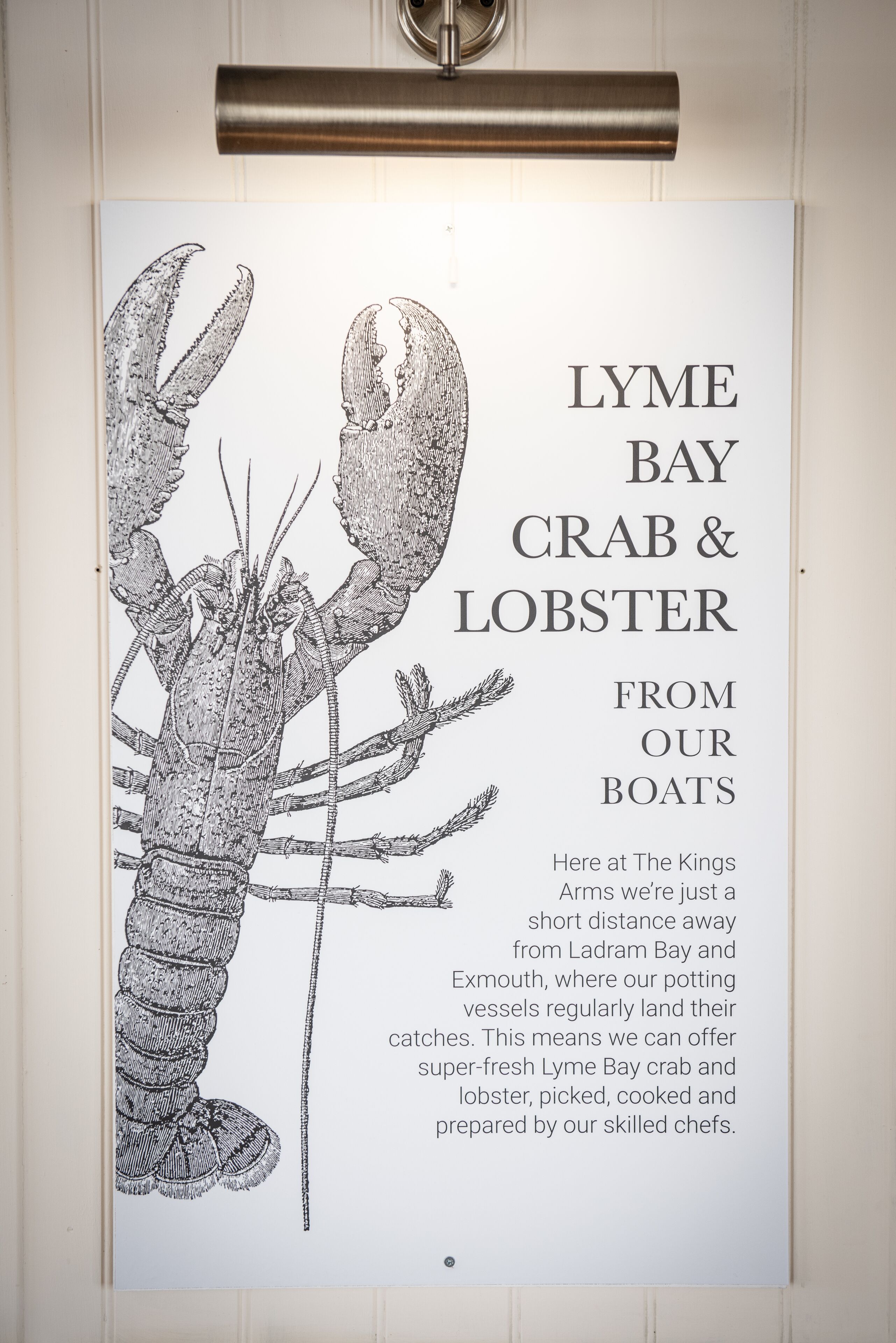 A menu board with a detailed illustration of a lobster and text describing the availability of fresh lobster and crab from boats.