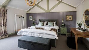 A bedroom with a bed, bedside tables, a desk, a hanging chair, and a mirror. - Kings Arms Otterton (Budleigh Salterton)