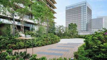 Un edificio moderno con fachada de vidrio, rodeado de exuberante vegetación y un sendero de madera.