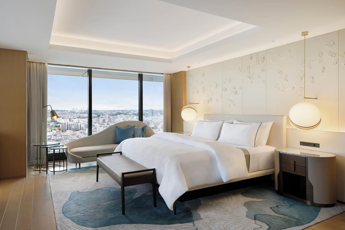 Una habitació d'hotel moderna amb un llit gran, una zona d'estar i vista a la ciutat.