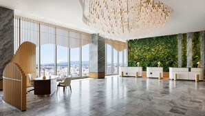 Un vestíbulo amplio con diseño moderno, que cuenta con un mostrador de recepción, zona de estar y grandes ventanales con vistas a la ciudad.