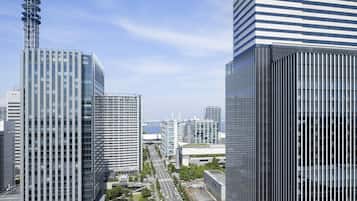 A cityscape with modern high-rise buildings, a clear sky, and a distant view of a body of water.