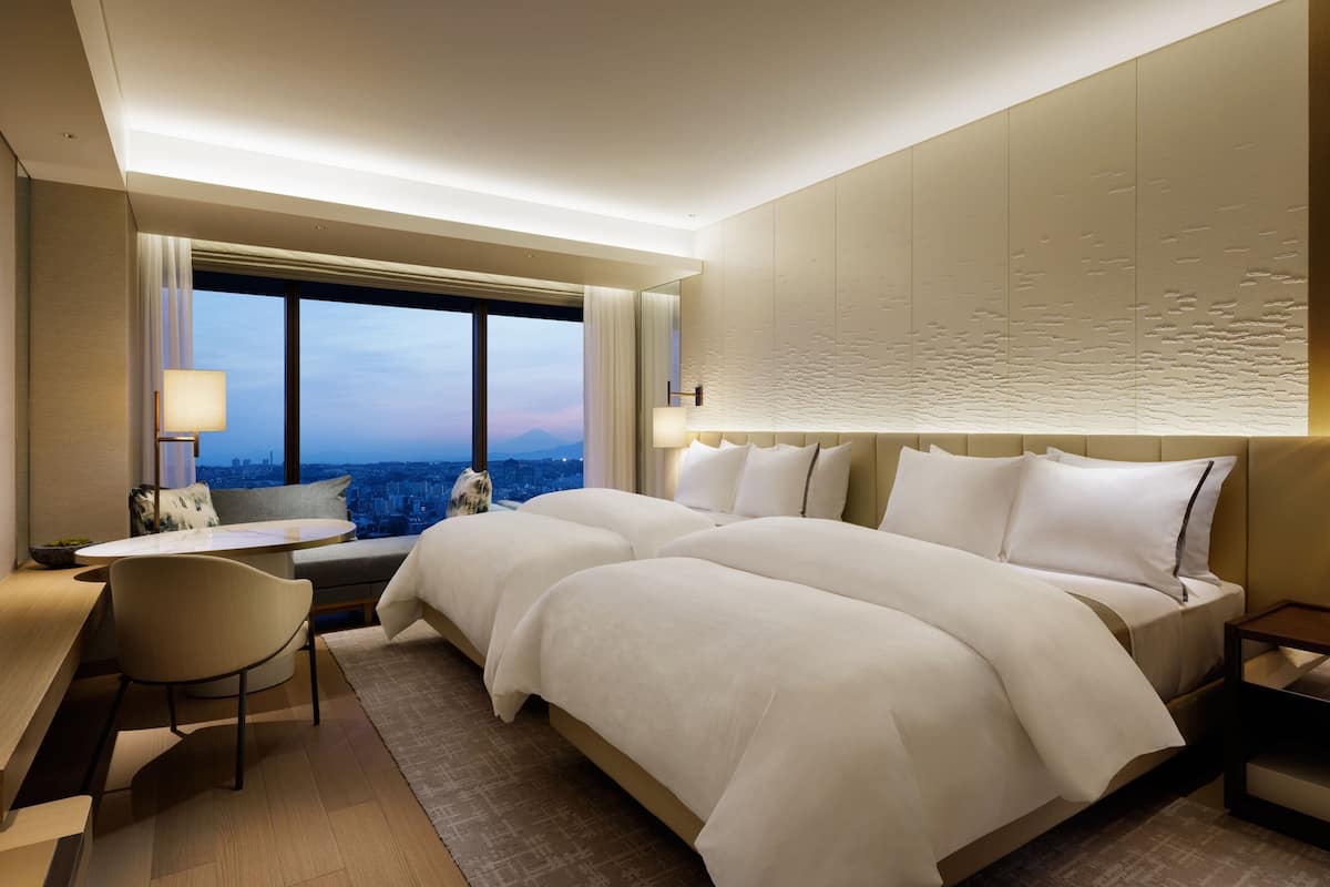 Habitació d'hotel moderna amb un llit gran, escriptori i vista a la ciutat.