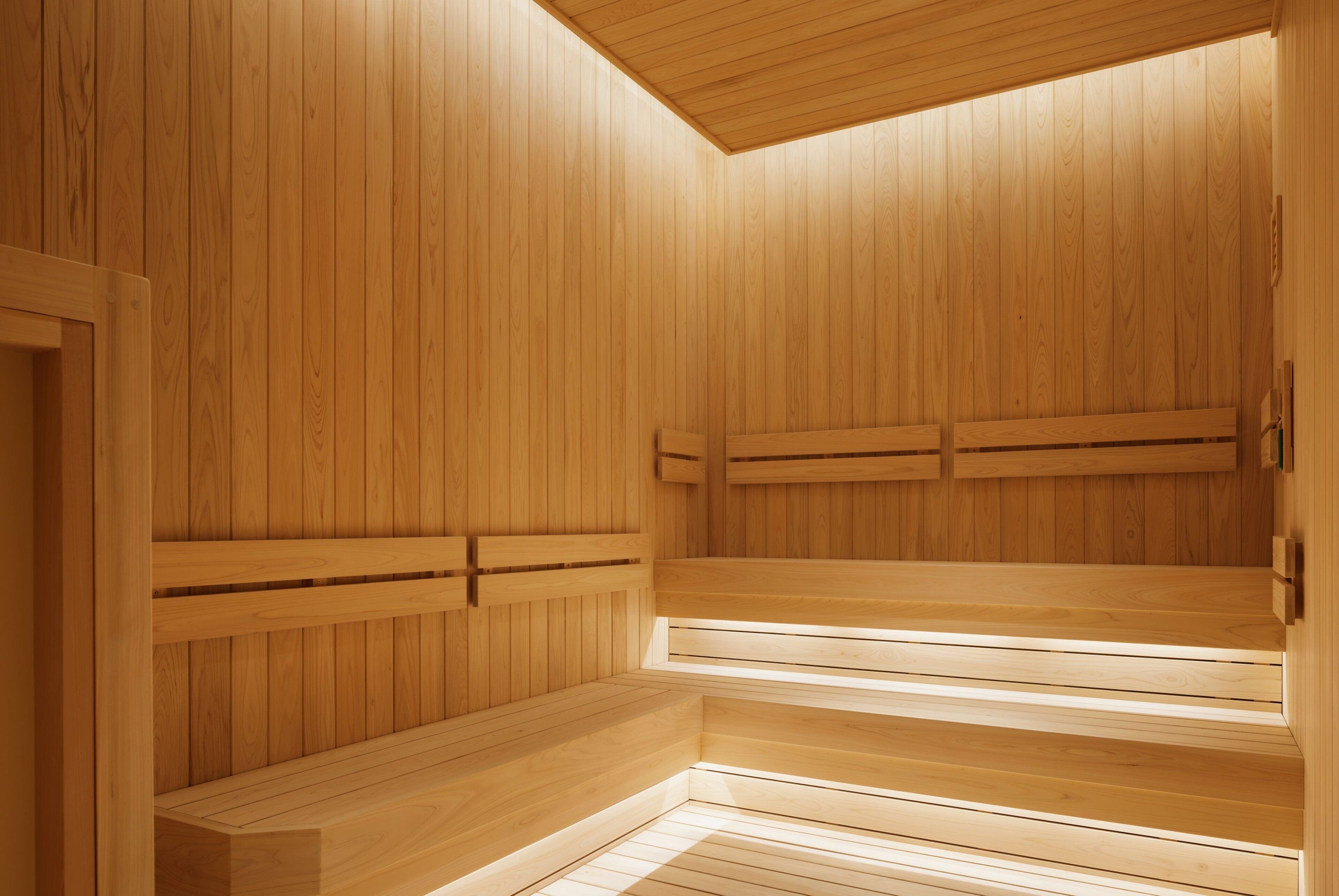 A wooden sauna with benches and a sloped ceiling.
