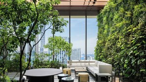 Terraza con pared verde, zona de estar y vistas a la ciudad.