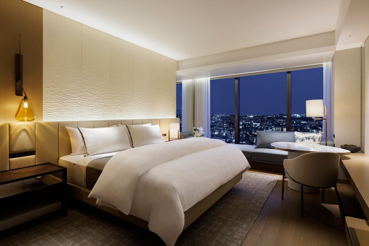 Habitació d'hotel moderna amb un llit gran, un escriptori i vistes a la ciutat de nit.