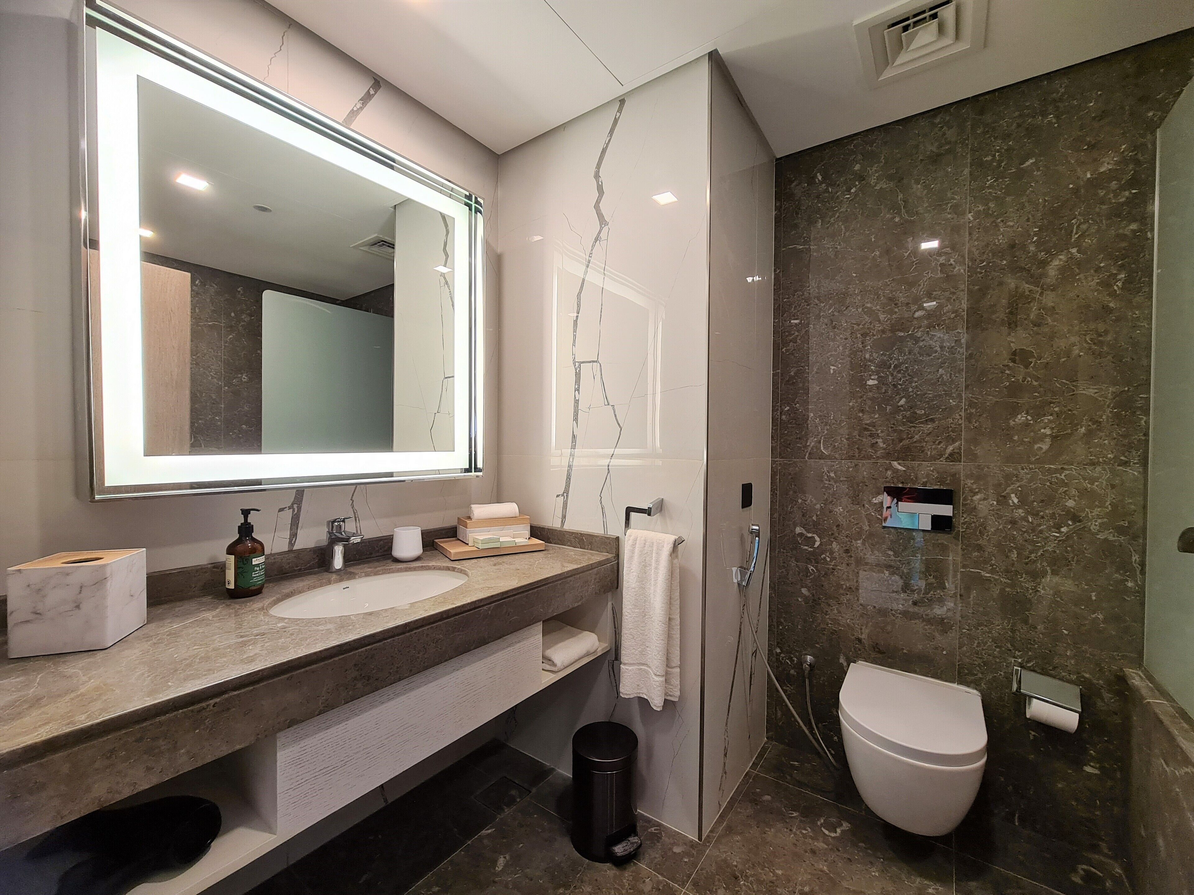 Un baño moderno con un espejo grande, dos lavamanos, un inodoro y una ducha.