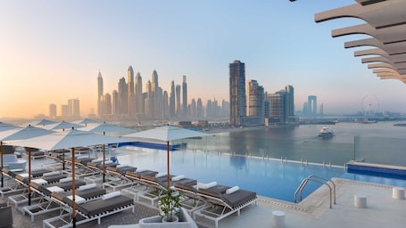 Outdoor pool, open 7:00 AM to 8:00 PM, pool umbrellas, pool loungers. voco Dubai the Palm by IHG