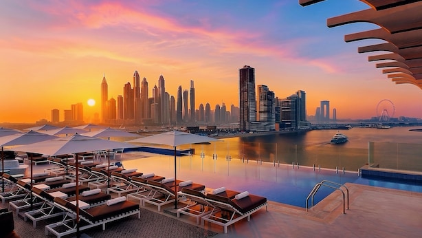 A rooftop pool with lounge chairs and umbrellas, overlooking a city skyline at sunset. - voco Dubai the Palm by IHG (Dubai)