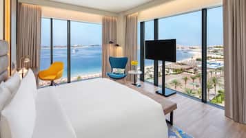 Habitació d'hotel amb un llit gran, televisió, una cadira i vistes a la platja i l'oceà.