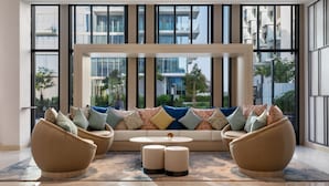 A modern living room with a sofa set, two armchairs, and a coffee table. Large windows offer a view of the cityscape. - voco Dubai the Palm by IHG (Dubai)