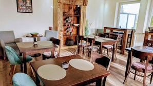 A spacious dining area with multiple wooden tables and chairs, a rustic wooden cabinet, and a framed artwork on the wall. - Hotel Tausendschön (Sudbrookmerland)