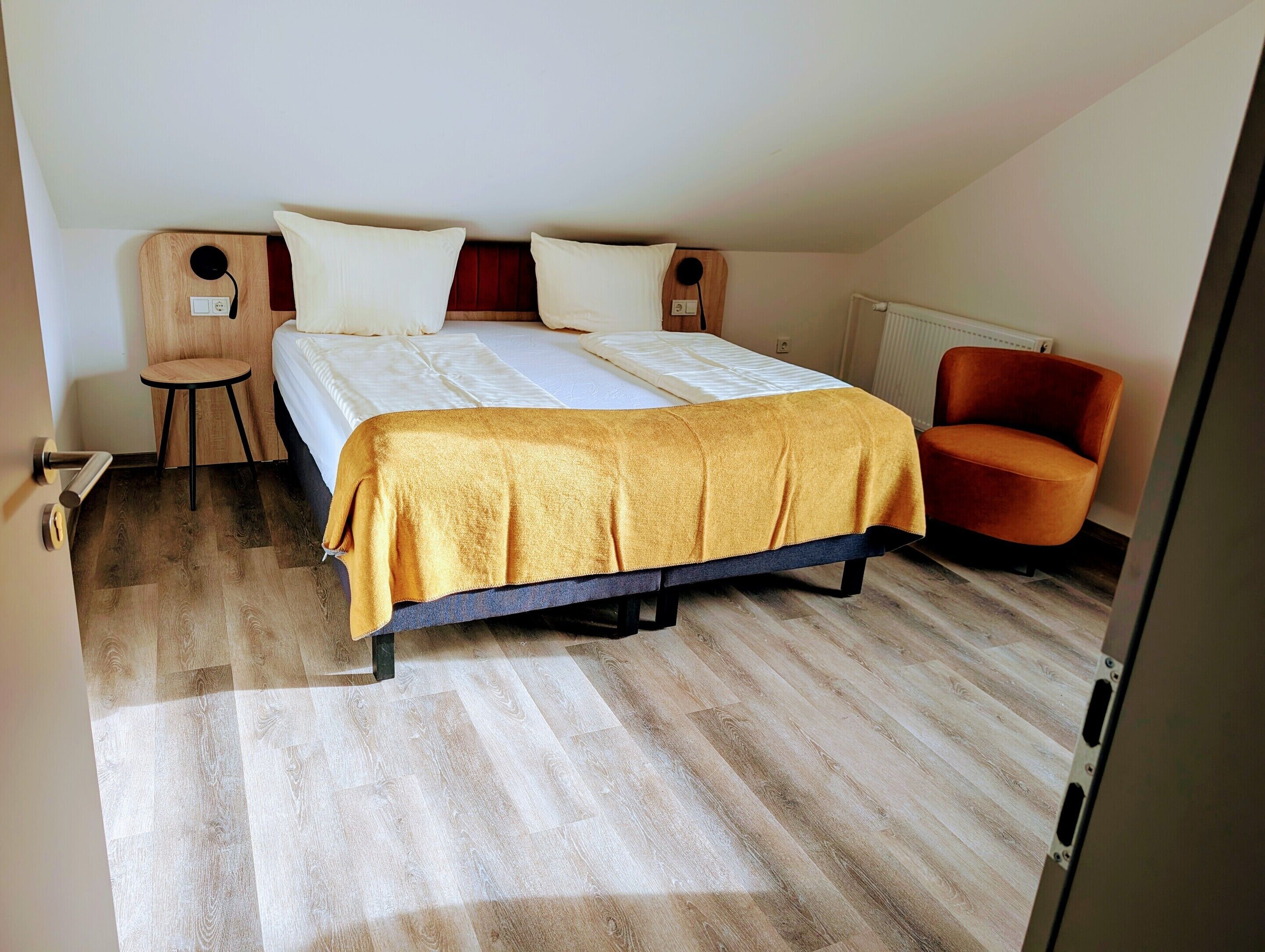 Un dormitorio con una cama, dos mesitas de noche, una silla y un radiador.