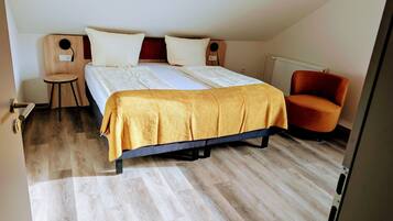 Un dormitorio con una cama, dos mesitas de noche, una silla y un radiador.