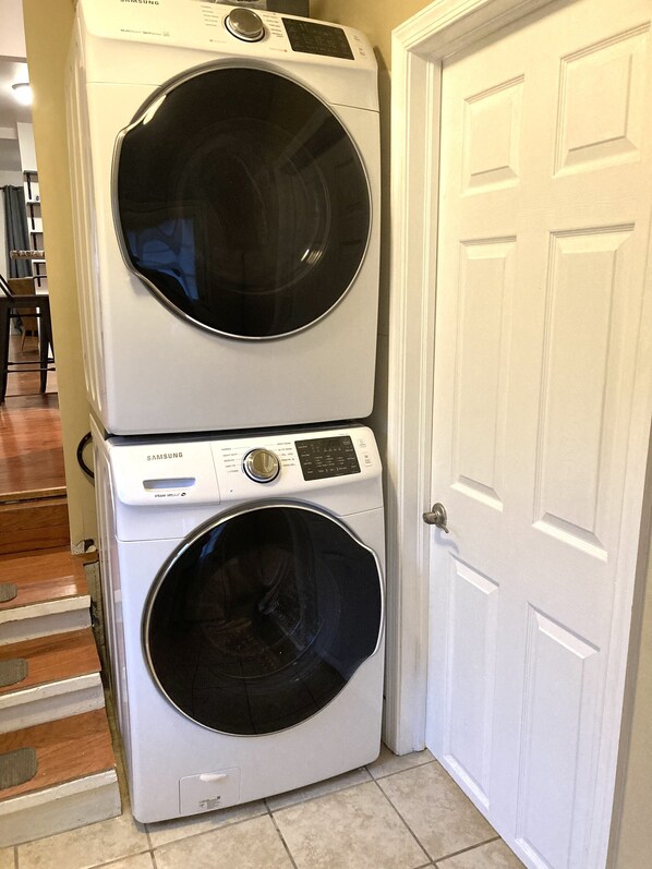 Une machine à laver et un sèche-linge superposés, installés dans un couloir.