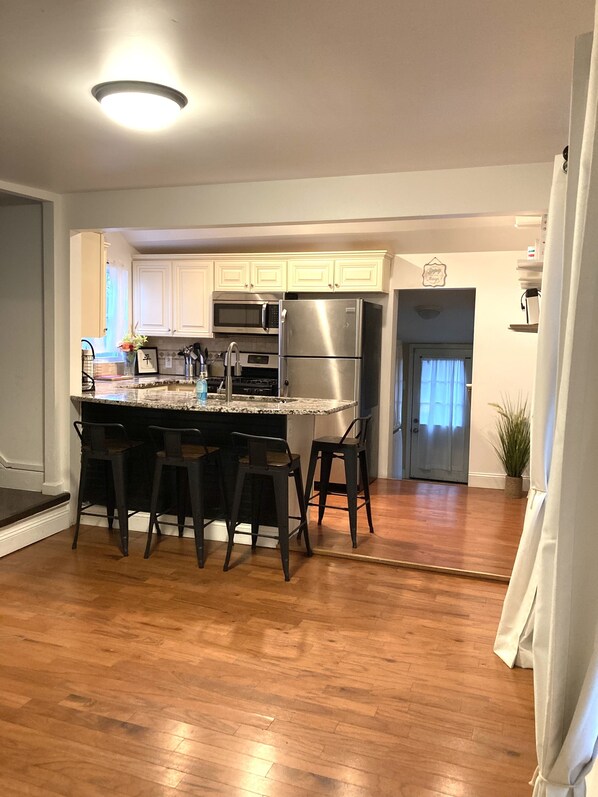 A modern kitchen with white cabinets, stainless steel appliances, and a central island with bar stools.