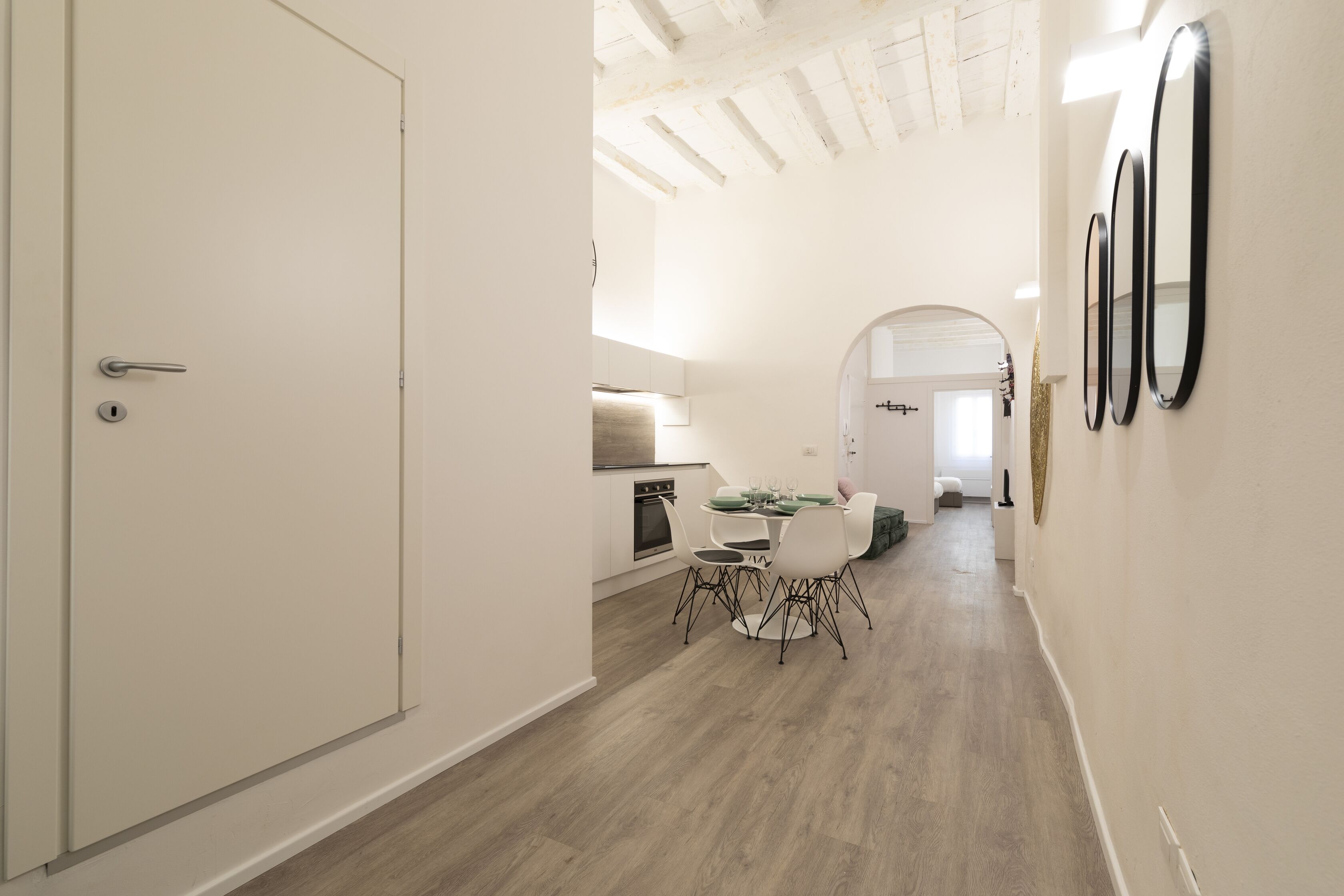 Un intérieur moderne comprenant un coin repas, une cuisine et un couloir menant à une autre pièce.