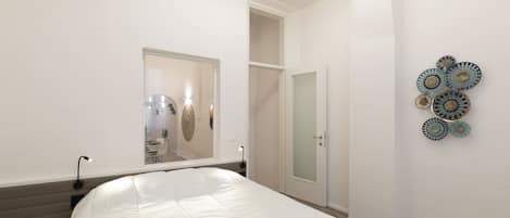 Un dormitorio con una cama grande, un armario y un espejo.