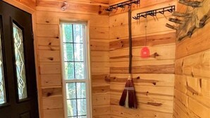 A wooden cabin interior with a large window, a wooden bench, and a hanging coat rack. - Mossy Moose (Packwood)
