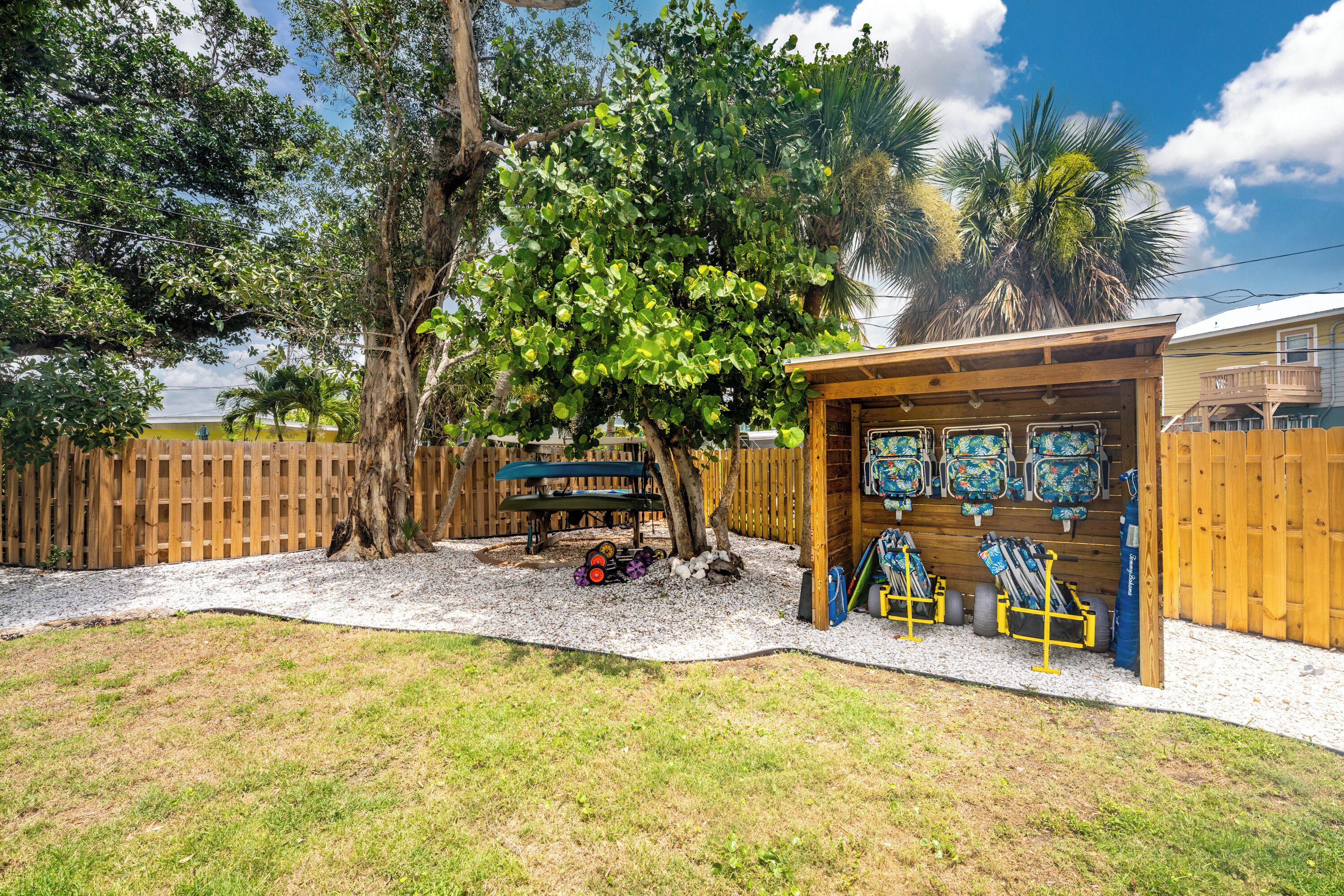 Patio trasero con terraza de madera, zona de estar cubierta y un árbol.
