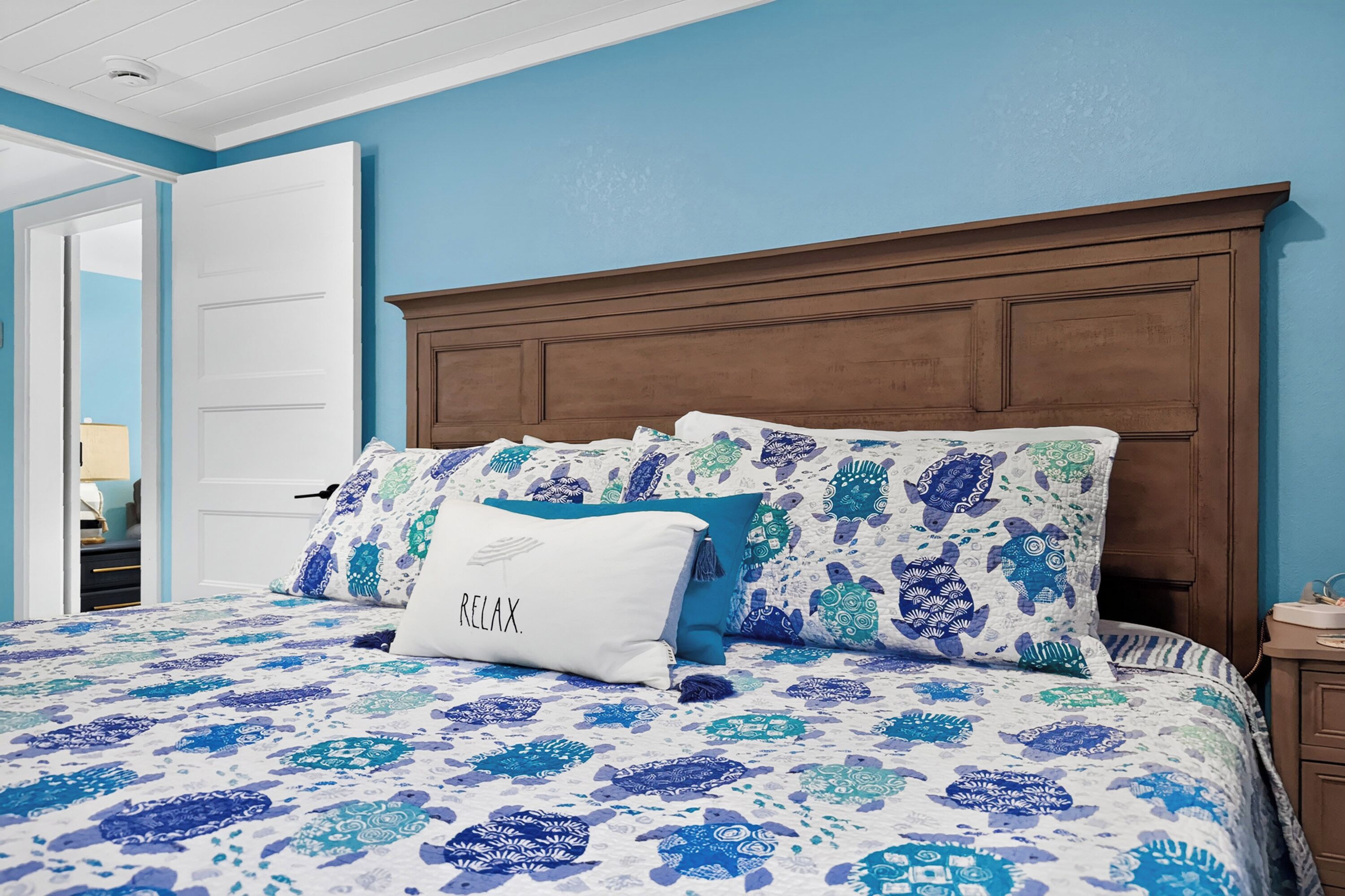 Une chambre à coucher comprenant un lit, une table de chevet, une porte et un mur aux couleurs bleues.