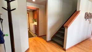 A staircase leading to a second floor, a coat rack, and a laundry room visible through an open door. - Elkhorn (Packwood)