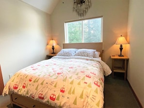 A bedroom with a bed, two bedside lamps, a window, and a chandelier. - Elkhorn (Packwood)