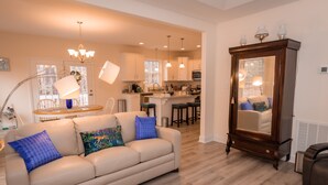 A modern living room with a beige sofa, a wooden cabinet, and a kitchen area in the background.