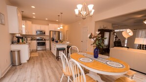 A modern kitchen with white cabinets, stainless steel appliances, and a wooden dining table with chairs.