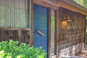A wooden exterior with a blue door and a window.