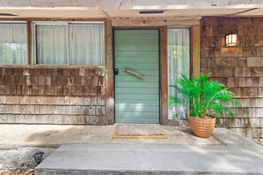Enter through the welcoming green door, flanked by a small potted plant and a concrete step.