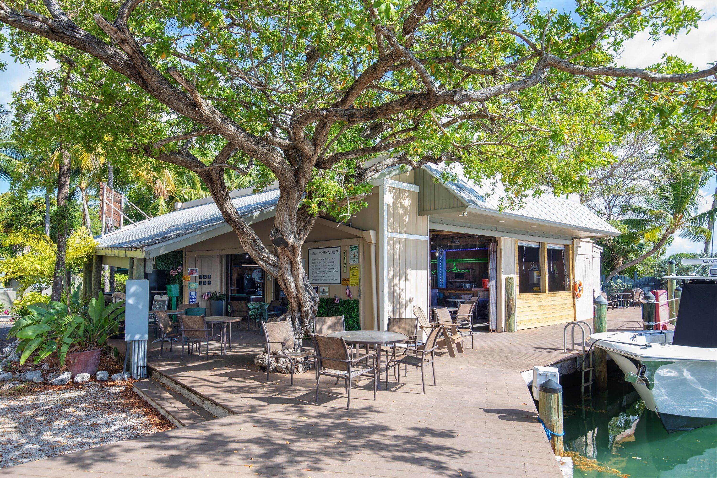 A waterfront restaurant with outdoor seating, a covered patio, and a dock for boats.