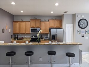 Enjoy cooking in this well-equipped kitchen with a microwave, oven, and refrigerator, plus a granite countertop and bar stools.