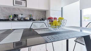 A modern kitchen with white cabinets, a microwave, a coffee maker, a blender, and a fruit bowl on the counter. - Torre Diez by Grupo Amber (Playa del Carmen)