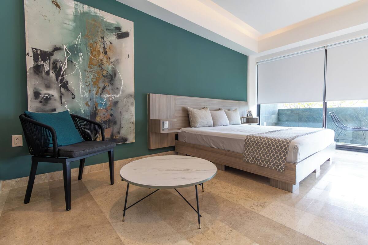 Een moderne slaapkamer met een groot bed, een ronde tafel en een bankje.